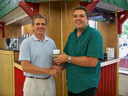 Two Men Shaking Hands and Holding Coffee Cups